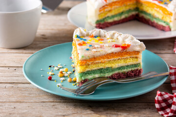 Rainbow layer cake piece on wooden table