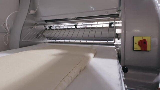 Automatic machine rolling dough for baking. Baking production. High quality 4k footage