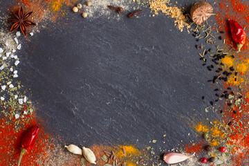 Variety aromatic spices in powder scattered on black stone background with free space 