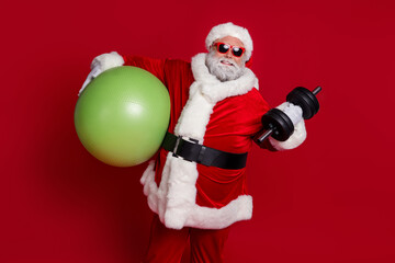 Portrait of attractive cheerful Santa working out doing effort lifting weight loss isolated over bright red color background