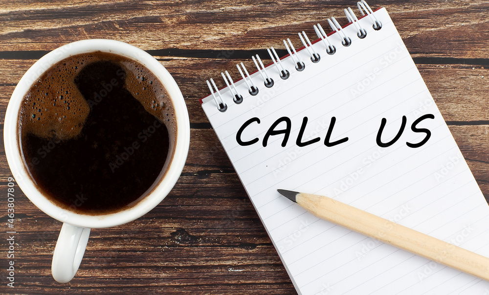 Poster call us text on notebook with coffee on the wooden background