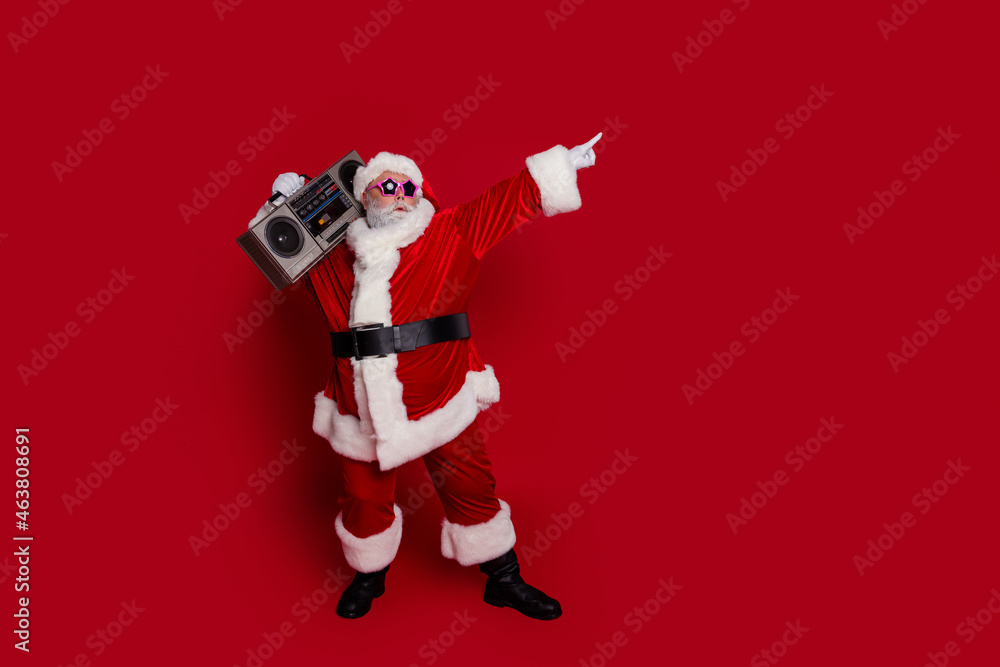 Poster Full size photo of funny body positive santa listen boom box index promo wear hat eyewear coat pants boots isolated on red background