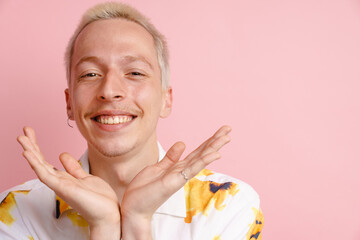 Young blonde man in shirt gesturing and smiling at camera