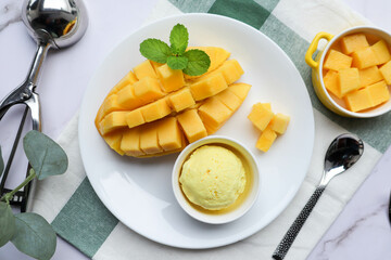Mango Ice cream with ripe mango on the side in white plate at top view