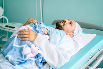 Newborn baby boy right after delivery, happy caucasian father with newborn baby lying skin to skin in hospital.