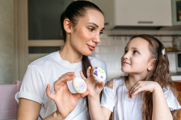 family traditions, mother and daughter at the table paint eggs for Easter