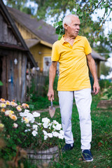 Old man with trowel beside flowerbed