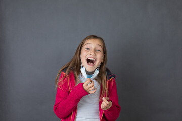 Portrait of a young happy girl trying to breath with open mouth in red sweater playing with medical...