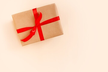 Christmas gift box with red bow on beige background. Holiday concept, New year presents.