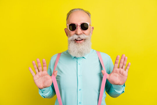 Photo portrait of elder man in teal shirt sunglass laughing touching suspenders isolated on bright yellow color background