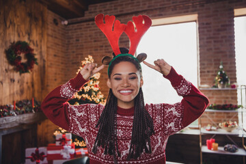 Photo of cheerful promoter direct fingers deer horns headband novelty sale wear jumper in decorated home indoors