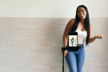 Woman recording a video vlog with her phone, dancing. Focus on the phone screen.