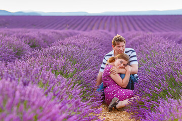 Romantic couple in love in lavender fields in Provence, France. Beautiful young man and woman hugging at sunset. Wedding or engagement.