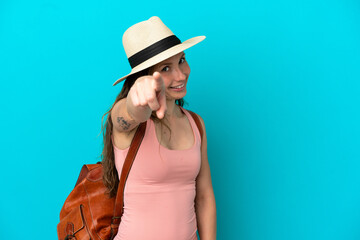 Young caucasian woman in summer holidays isolated on blue background points finger at you with a confident expression
