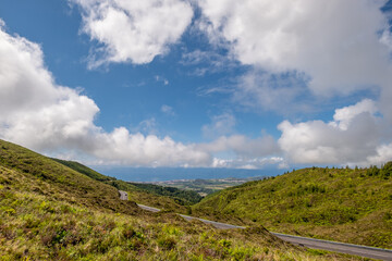 Fototapeta na wymiar Road with beautiful view to the north coast of the island and the green vegetation near the Fire Lagoon (Lagoa do Fogo) on a summer day afternoon. São Miguel Island in the Azores.