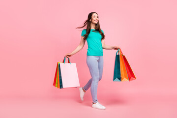 Full length profile side photo of young woman happy positive smile walk shop sale hold bags isolated over pastel color background