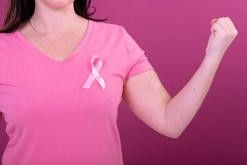 Midsection of caucasian woman in pink tshirt with ribbon and clenched fists