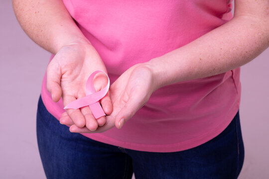 Hands of caucasian woman in pink tshirt holding pink ribbon