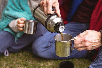 Mid section of man pouring coffee in a cup while sitting in a tent in the garden
