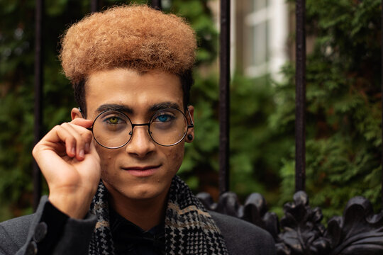 Portrait of handsome young black man with heterochromia wearing round eyeglasses outdoors (selective focus on eyes)