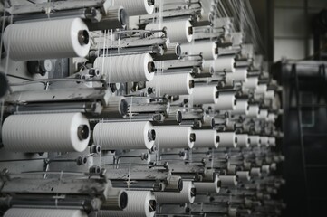 Coils of white flat polypropylene yarn for the production of industrial bags. circular loom woven bag machine. Production of polypropylene sleeves.
