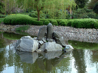 Fototapeta na wymiar Asian park in Europe. Beautiful, incredibly refined and arranged in the Asian style garden. Full of greenery, stones and water. With a gentle hum, it calms our nerves.