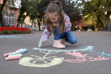 Child drawing family with chalk on asphalt