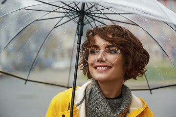 Girl in yellow raincoat with transparent umbrella
