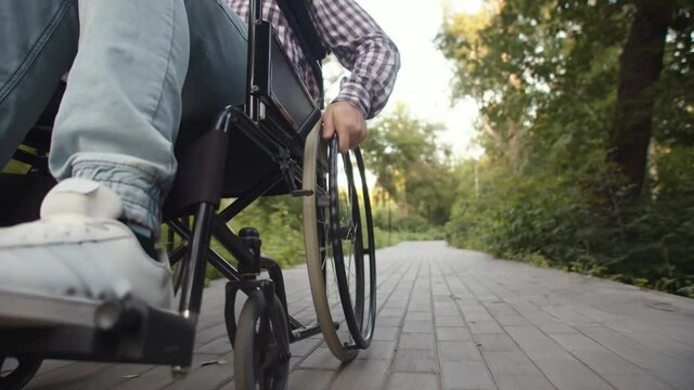 Moving wheelchair driven by disabled person man, closeup. Concept of consequences of car accident and diagnosis paralysis