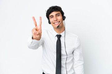 Telemarketer man working with a headset isolated on white background smiling and showing victory sign