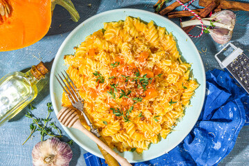 Creamy cheesy vegan pumpkin pasta, fusilli with pumpkin squash sauce, cheese and thyme, on concrete...