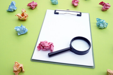 Magnifying glass, clipboard and crumpled colorful stickers around.