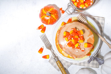 Homemade candy corn pancakes. Stack of yellow and orange pancakes with sweet sauce and traditional Halloween candy cord candies