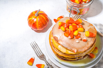 Homemade candy corn pancakes. Stack of yellow and orange pancakes with sweet sauce and traditional Halloween candy cord candies