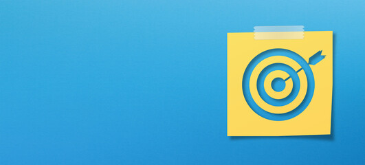 Yellow sticky note paper and target sign with copy space on panoramic blue background