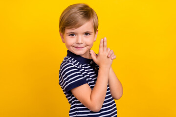 Photo portrait little boy wearing casual clothes keeping fingers like gun isolated bright yellow color background