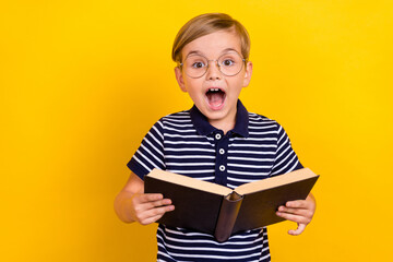 Photo portrait little boy wearing t-shirt glasses amazed reading book isolated vibrant yellow color...