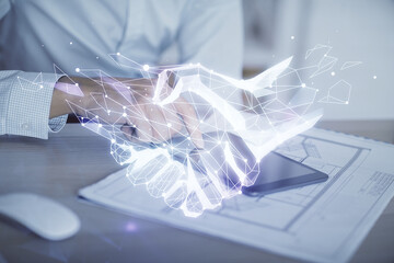 Double exposure of man's hands holding and using a digital device and handshake drawing. Partnership concept.