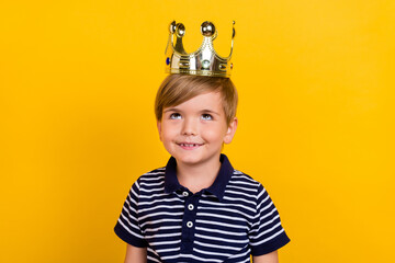 Photo portrait little prince wearing golden crown smiling dreamy isolated vibrant yellow color background - obrazy, fototapety, plakaty