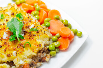 Shepherd's pie, tender minced lamb with garden veg in a hearty gravy beneath butter mash with carrots and green peas