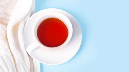 Hot winter cup of tea with white sweater or plaid nearby. Warm and cozy. Copy space.