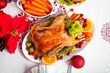 Table served for thanksgiving or Christmas dinner. Stuffed roasted turkey in the foreground. Traditional celebrating holiday.