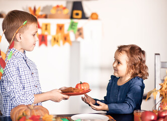 Kids served festive table and decorating living room for celebrating Thanksgiving day.