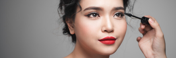 Naklejka premium woman applying cosmetic mascara on eyelashes using curling brush