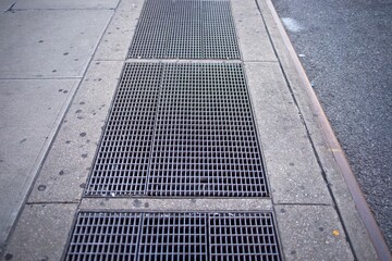 Subway vents on a sidewalk alongside a city street
