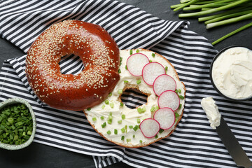 Delicious bagel with cream cheese, green onion and radish on table, flat lay