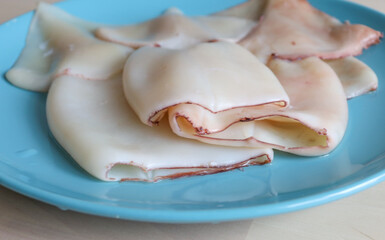 the squid carcass lies on a plate on the table. Proper nutrition, protein, seafood, affordable...