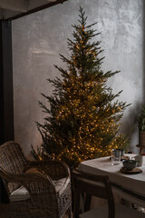 Modern home interior design. Comfortable cozy living room decorated with Christmas tree, rattan chair, table. Christmas, New Year holidays celebration