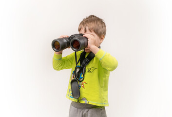 The boy looks through binoculars. Photo in the studio. space for text