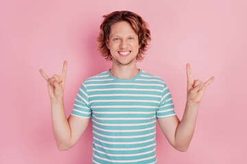 Photo of positive rocker man show horns gesture wear casual blue striped t-shirt on pink background